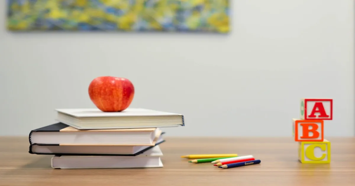 Bureau d'ecole avec des livres empiles, une pomme et des crayons de couleur, evoquant les souvenirs scolaires et le TDAH non diagnostique